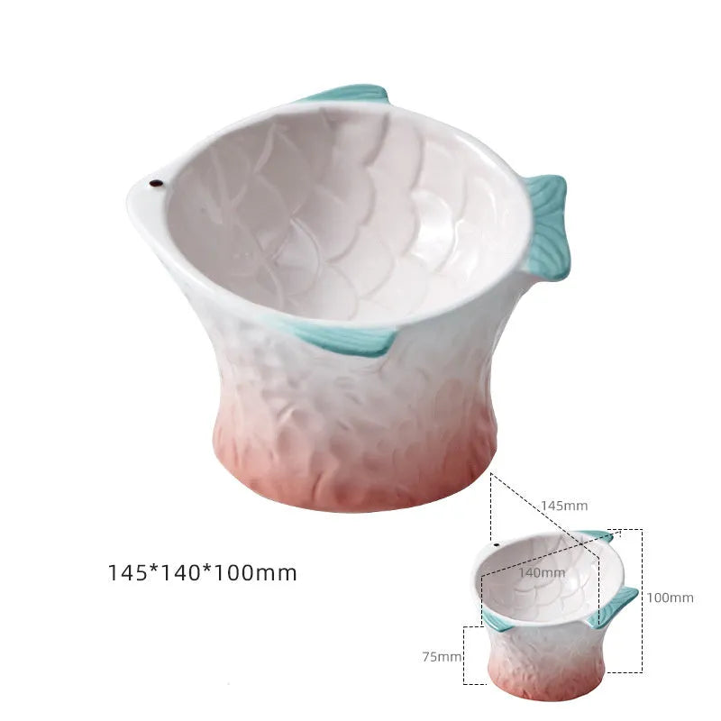 Four coloured fish-shaped ceramic pet bowls with a tilted, elevated design on a plain surface.