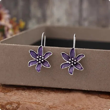 Close-up of a pair of purple flower-shaped alloy stud earrings with an electroplated finish.