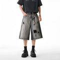 Grey loose fit denim shorts with distressed holes and a cropped length on a hanger.