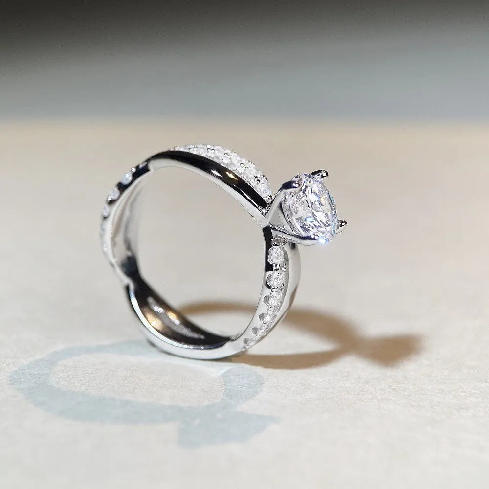 Silver geometric ring with a twisted band, a cross design, and a 1 karat moissanite in a four-claw setting.