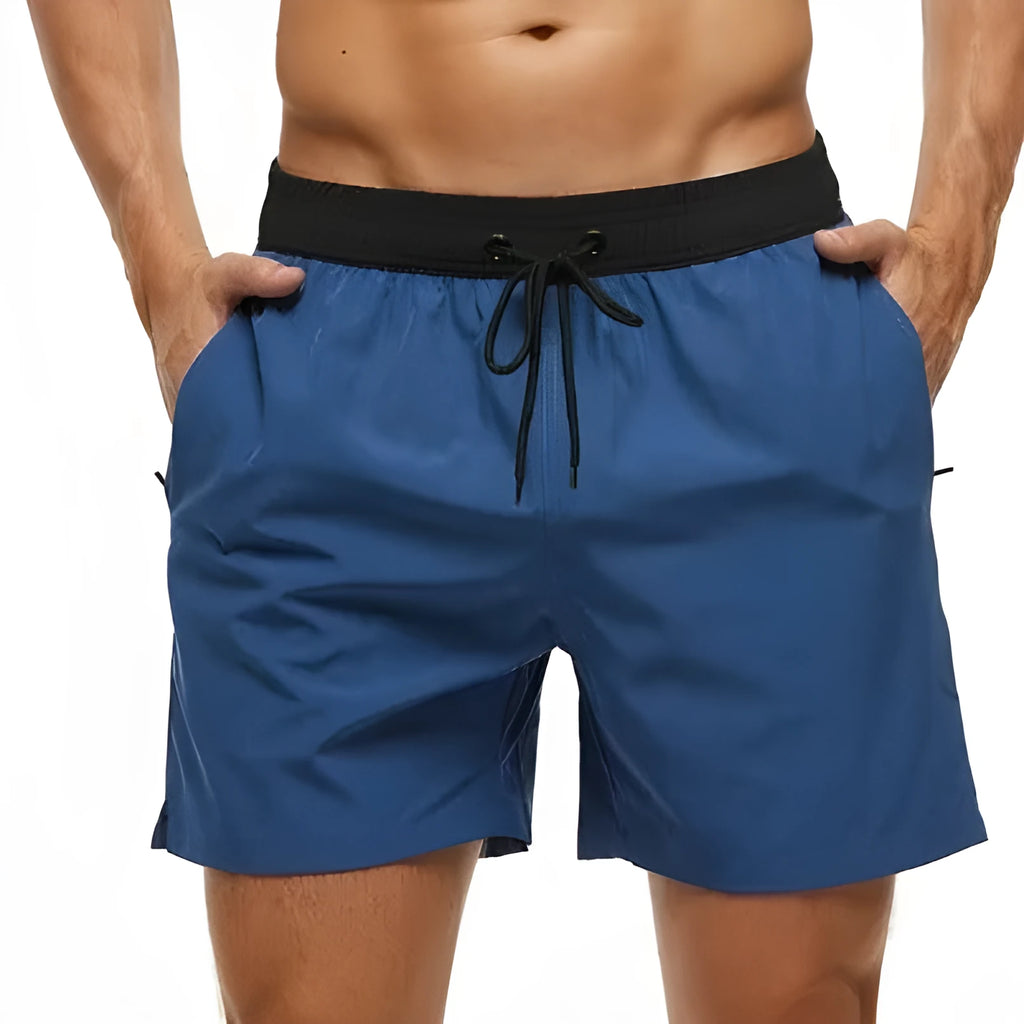 Blue men's fitness shorts with drawstring waist, pockets, and a zipper on a neutral background.