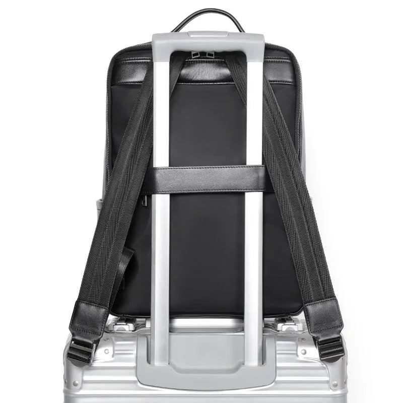 Men's black genuine leather computer backpack with curved back plate showing litchi grain texture and substantial 36-55L capacity.