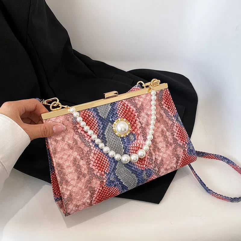 Hard PU evening bag in snake pattern with pearl-chain detail and stitching, available in six colours