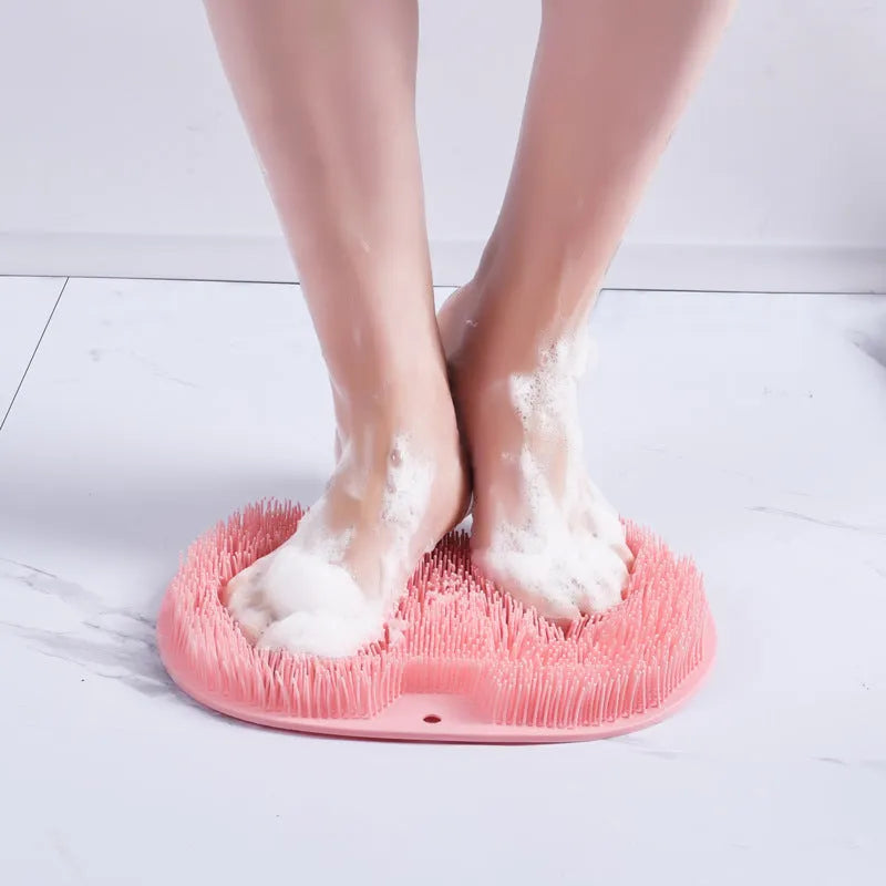 Orange silicone bristle bath brush with suction cup base on bathroom tiles.