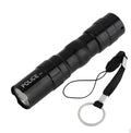 Small black aluminium LED flashlight showing compact size next to a AA battery for scale.