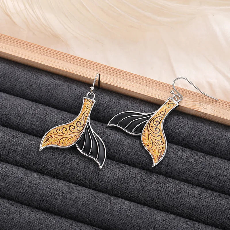 A pair of women's retro-style fishtail earrings with a whale decoration in white gold colour.