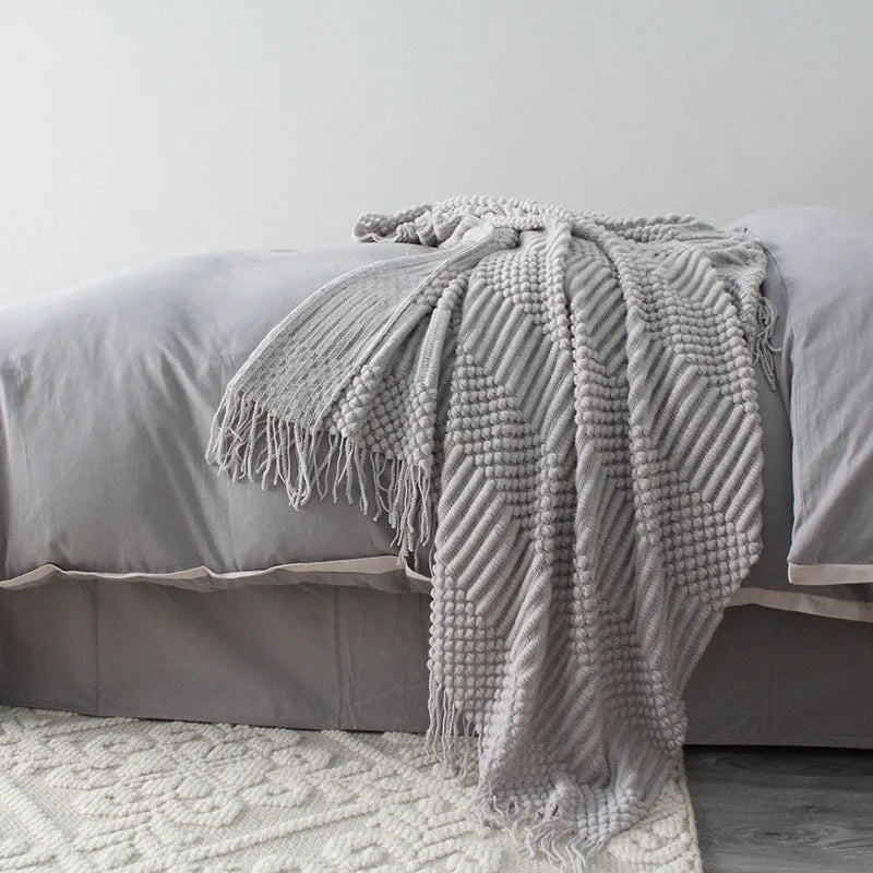 Small light grey polyester fibre blanket measuring 127 by 170 centimetres, folded on a sofa.