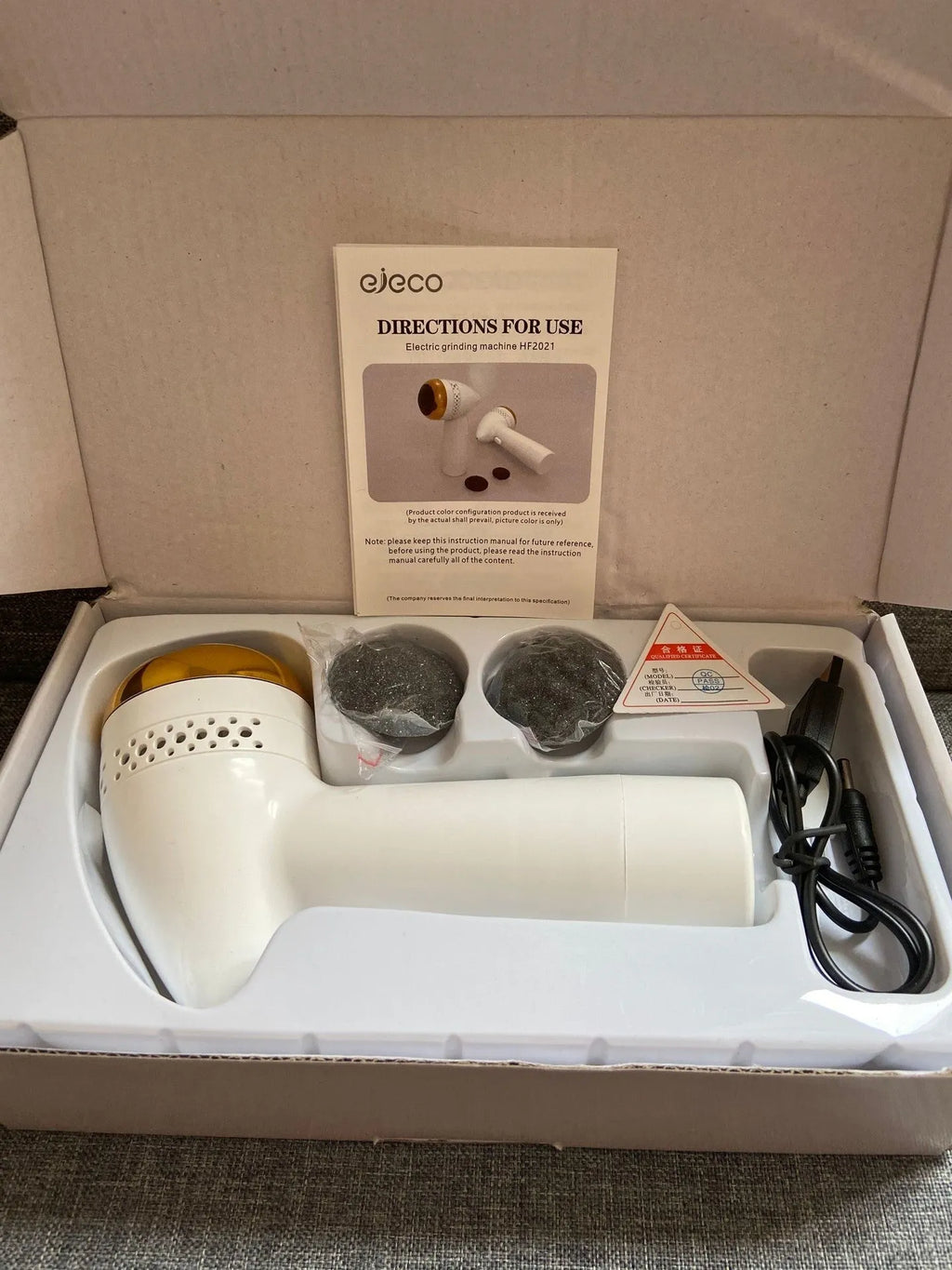 Electric vacuum foot grinder with quartz grinding head in a metallic finish, shown removing calluses on dry skin.