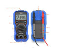 Handheld digital multimeter on a workbench with test leads, showing a large LCD display.