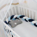 Braided knot design crib bumper in spandex velvet, shown in a light grey colour wrapped around crib slats.