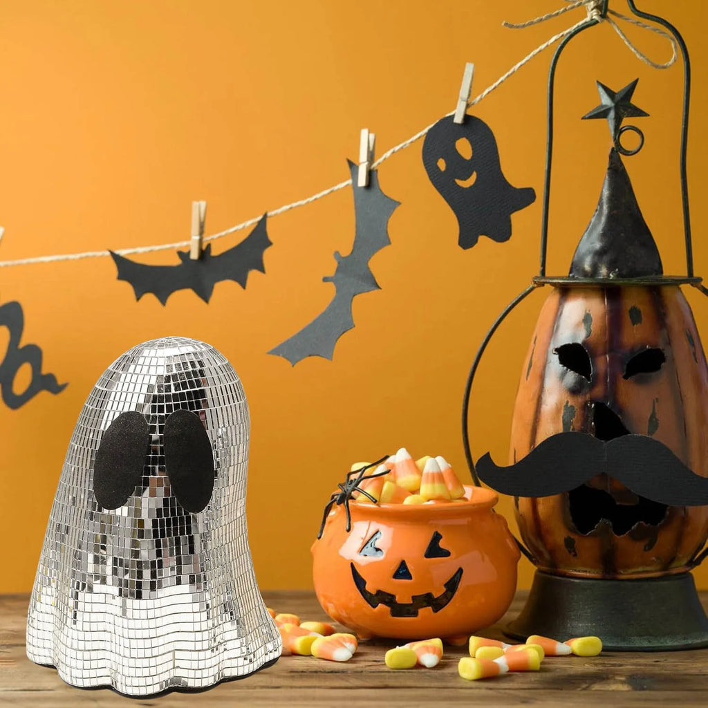 Silver glass ghost decoration with mosaic mirror patch on a desktop for Halloween.