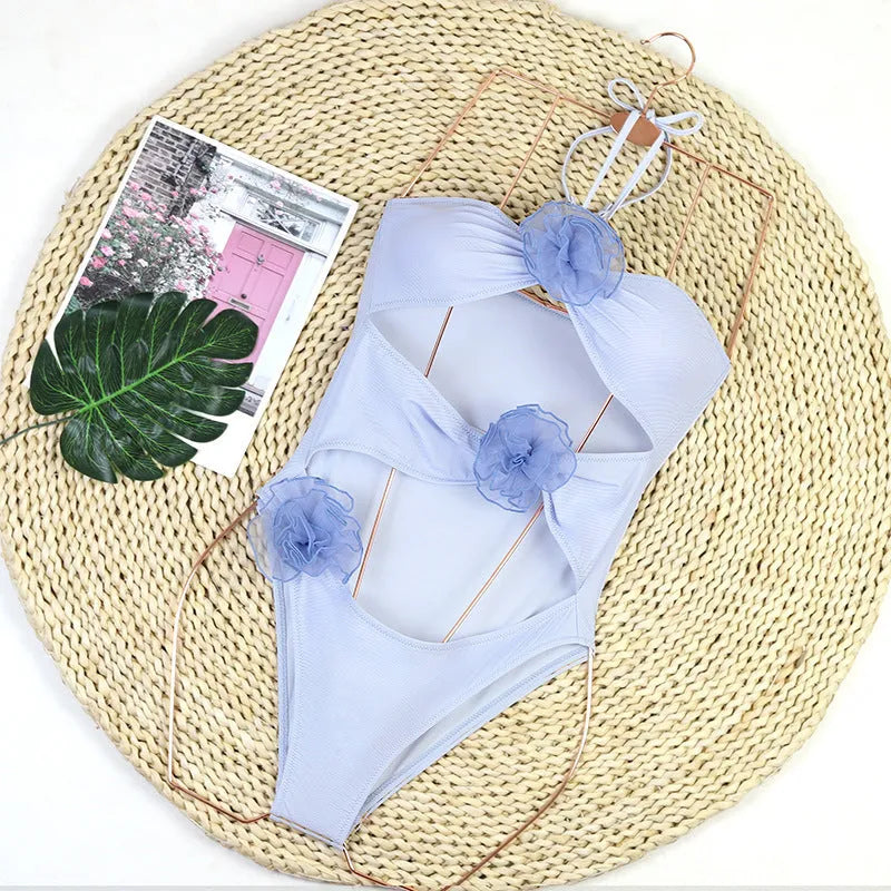 Women's black and blue striped one-piece swimsuit with 3D floral design on the front.