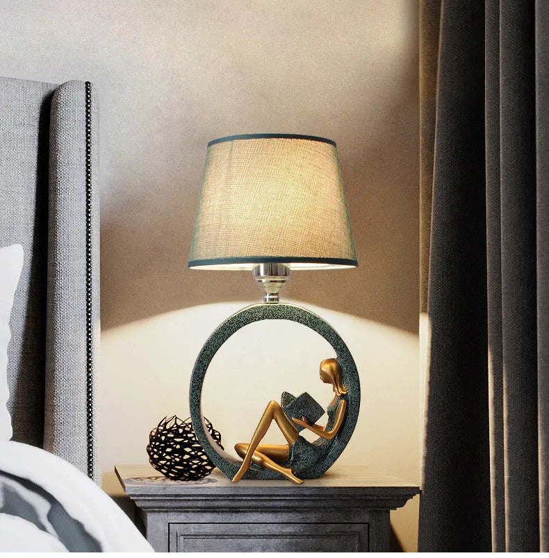 Blue resin reading girl table lamp with cloth shade on a table, 20x39.8cm