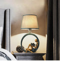 Blue resin reading girl table lamp with cloth shade on a table, 20x39.8cm