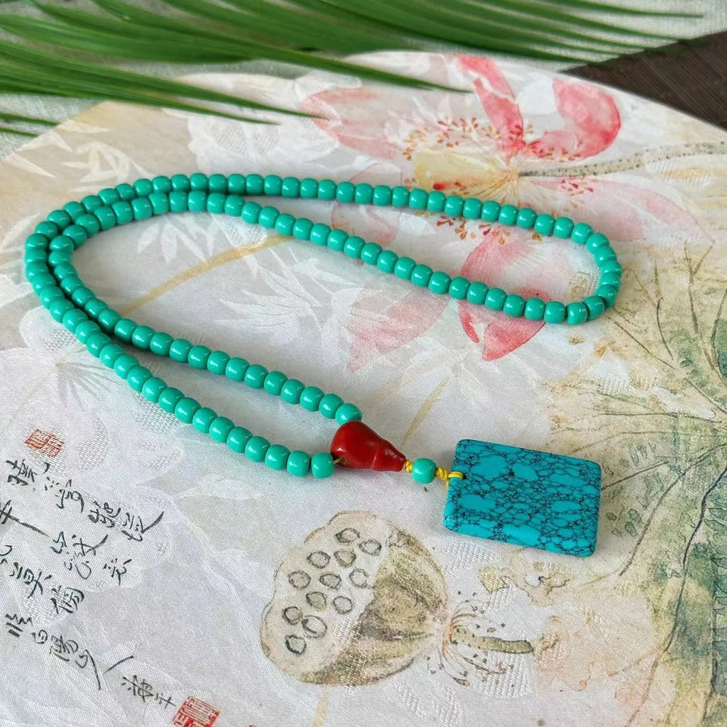 Hand-woven turquoise mesh flower lucky pendant necklace on a ball bead chain.