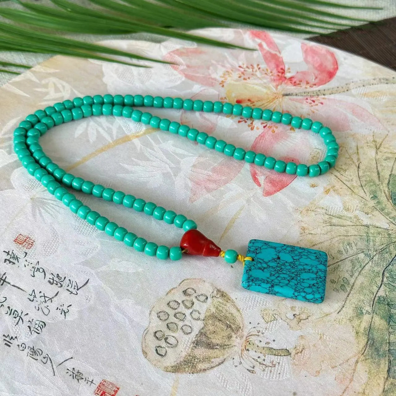 Hand-woven turquoise mesh flower lucky pendant necklace on a ball bead chain.