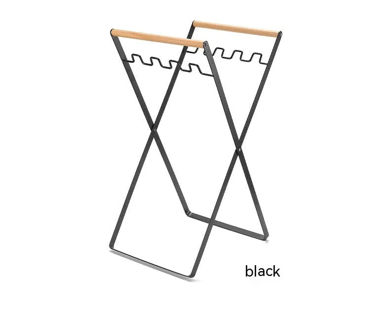 Black outdoor folding iron trash rack with wooden handle holding a rubbish bag.