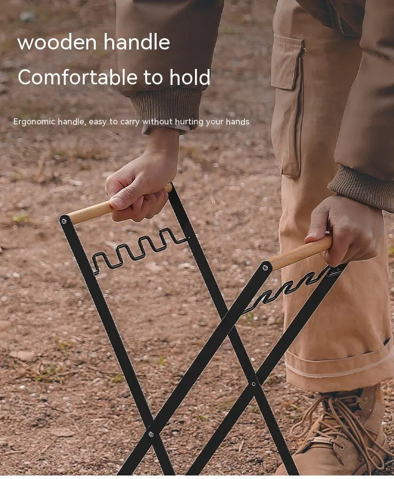 Black outdoor folding iron trash rack with wooden handle holding a rubbish bag.
