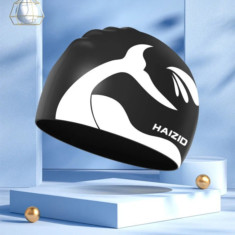 Silicone swimming cap with waterproof ear covers and a whale tail pattern in assorted colours.