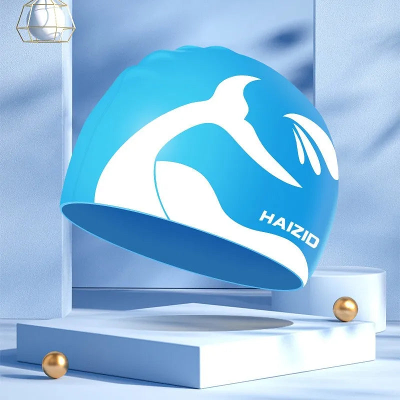 Silicone swimming cap with waterproof ear covers and a whale tail pattern in assorted colours.