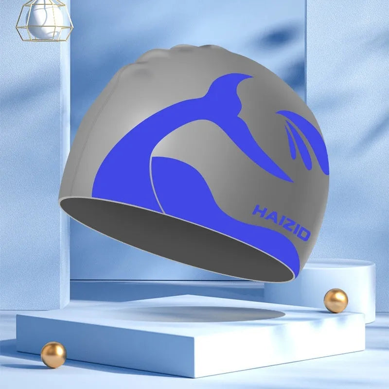 Silicone swimming cap with waterproof ear covers and a whale tail pattern in assorted colours.
