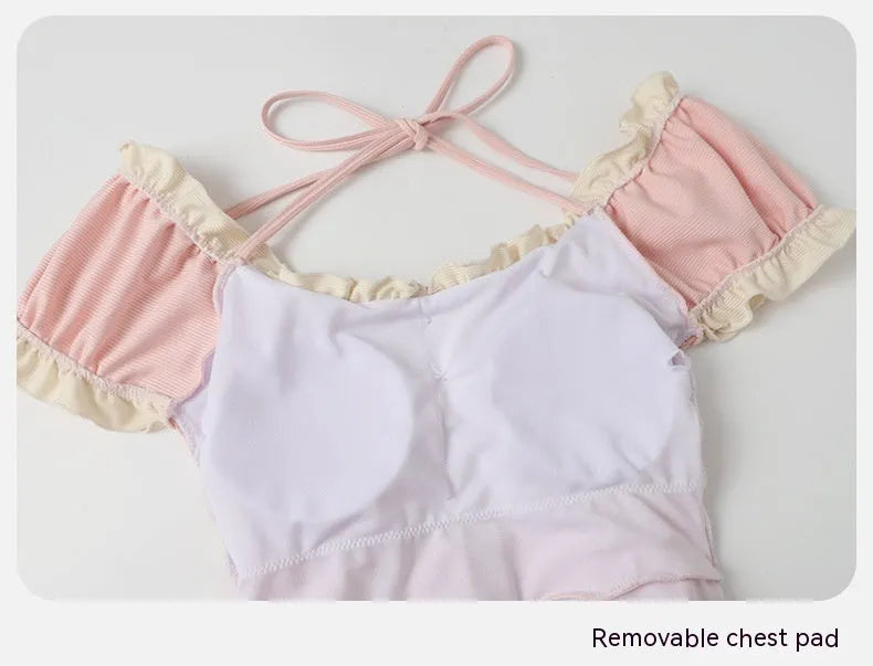 Pink women's one-piece swimsuit with conservative cut and Siamese cute design on a hanger.