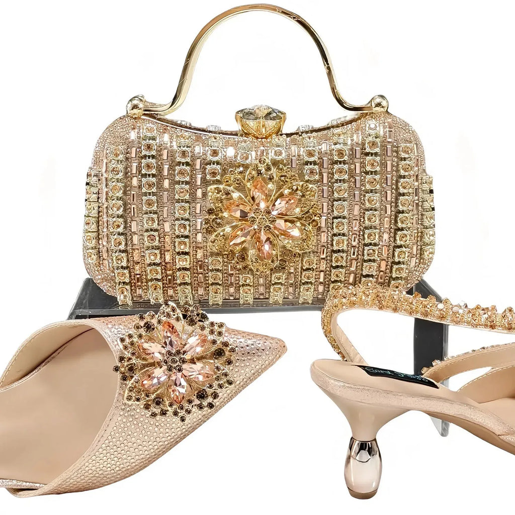Women's black high heel ankle-strap sandals with floral buckle and chain detail next to matching clutch bag