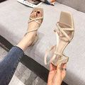 Women's white Roman gladiator sandals with a thick high heel and open side design on a plain background.