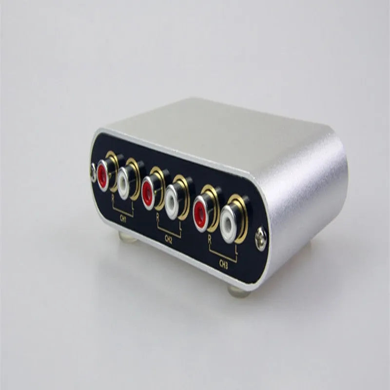 Silver aluminium audio source selector switch box with front button and infrared remote control.