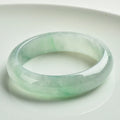 Light green jade bracelet showing natural stone colouration with size markings from 53 to 64