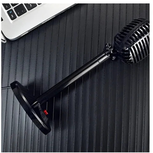 Black USB computer microphone with adjustable stand on desktop for recording and podcasting