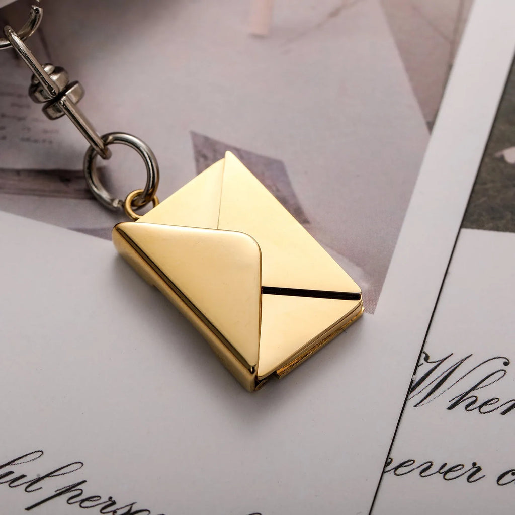 Stainless steel keychain with engraved card inside, shown in silver or gold envelope style