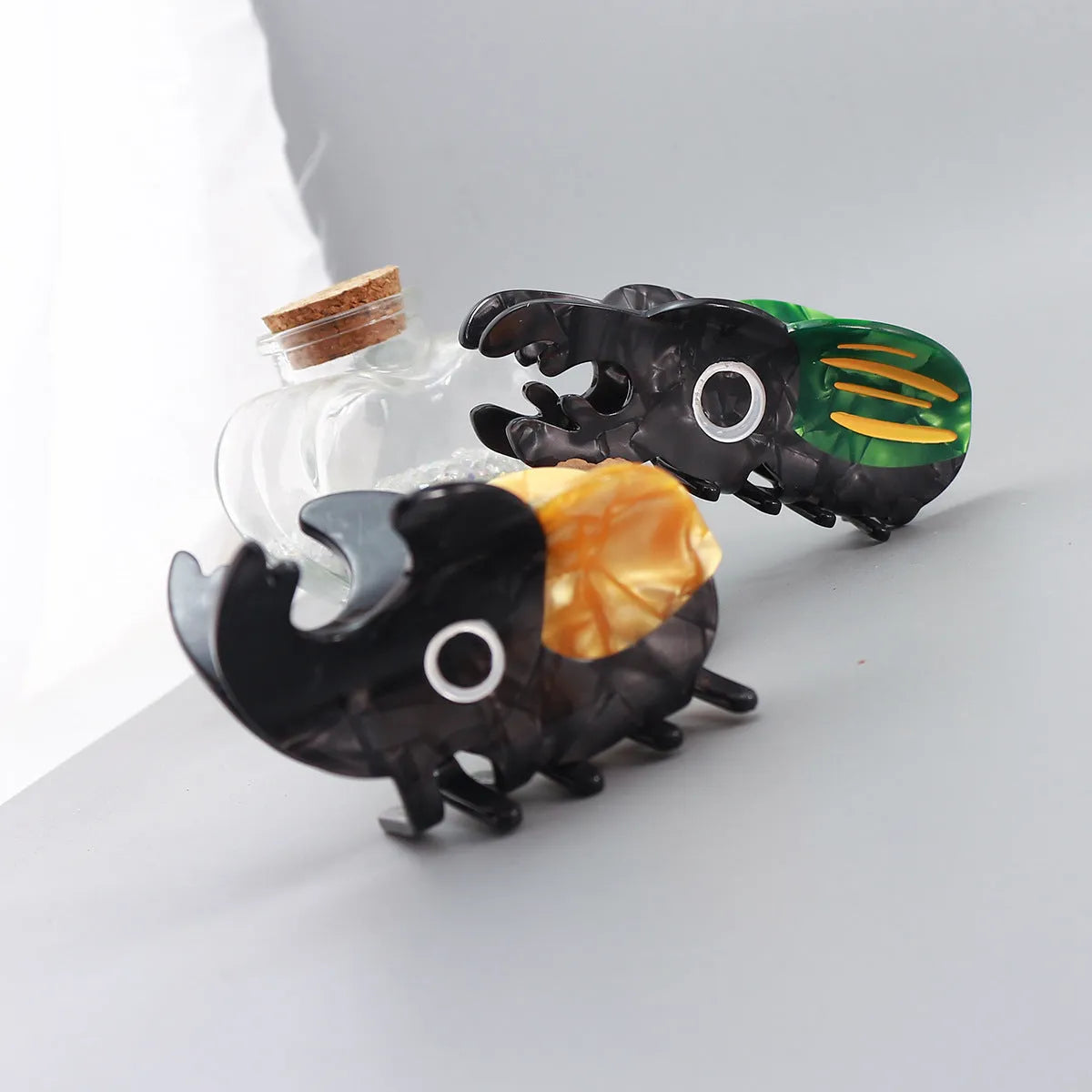 Handmade cartoon beetle grip brooch made from cellulose acetate in green, orange, or white insect designs.