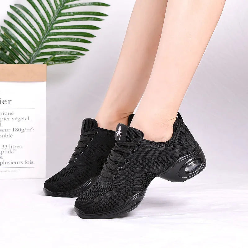 Women's breathable flyknit mesh dance shoes with a light PU sole on a wooden floor.