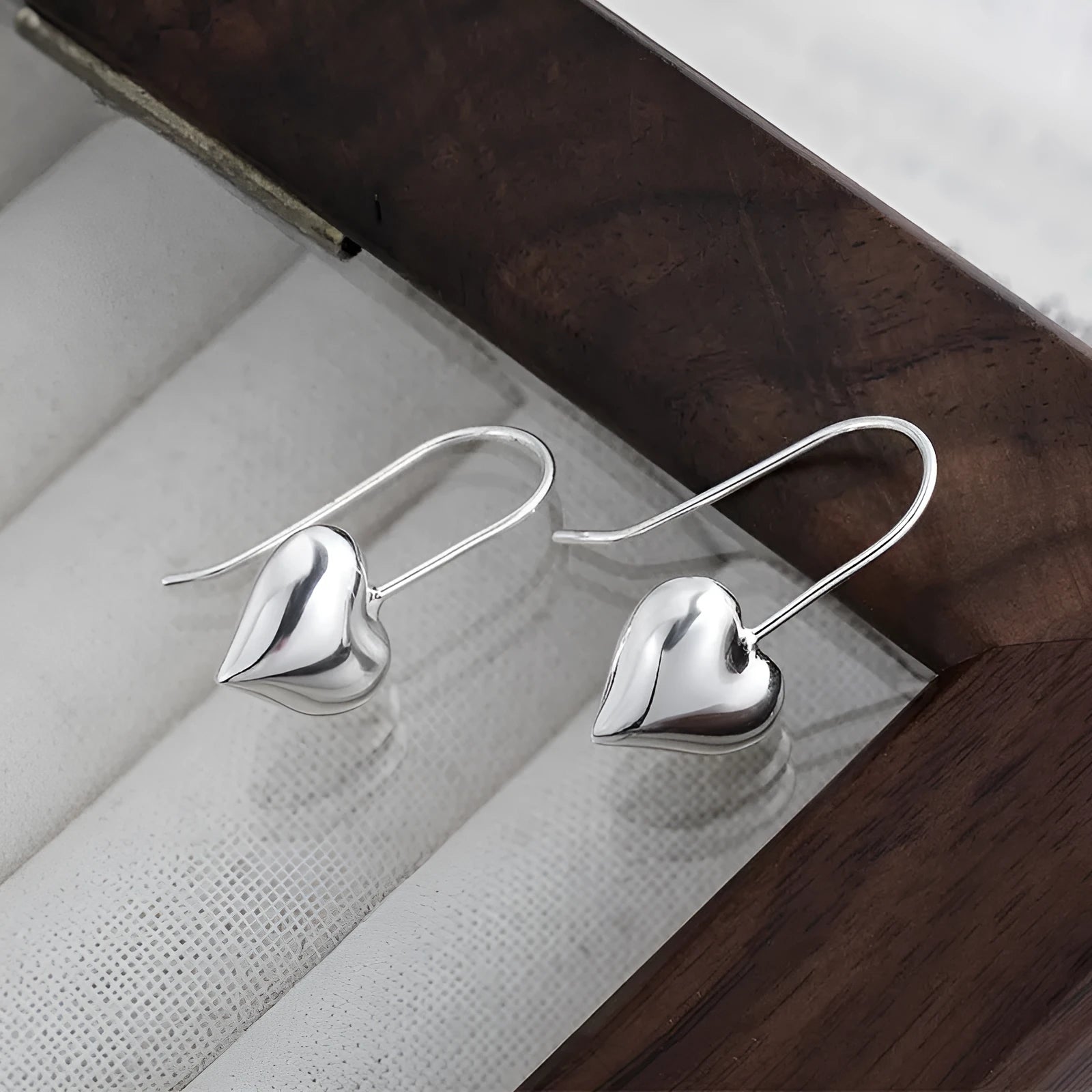 Silver heart-shaped earrings with glossy finish and three-dimensional Korean-style design