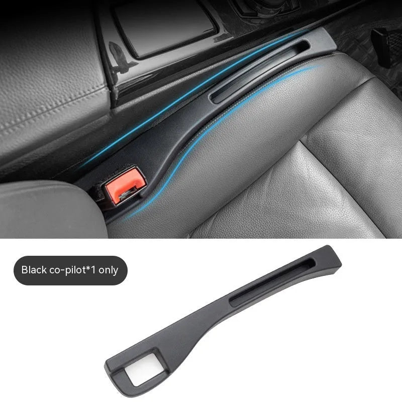 Black plastic car seat gap storage organiser box with a handle, shown inserted between vehicle seats.