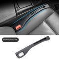 Black plastic car seat gap storage organiser box with a handle, shown inserted between vehicle seats.
