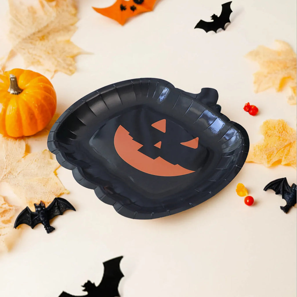 Black pumpkin design disposable paper plates measuring 9 inches in diameter, shown in Halloween party setting.