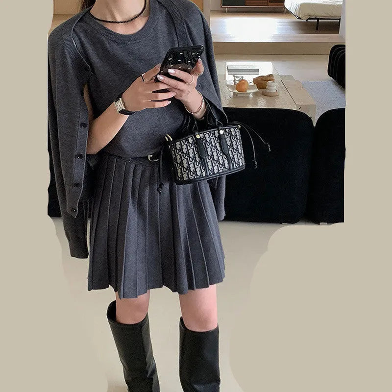 Women's black knitted two-piece set showing vest skirt with belt and long-sleeved cardigan with 3D pattern
