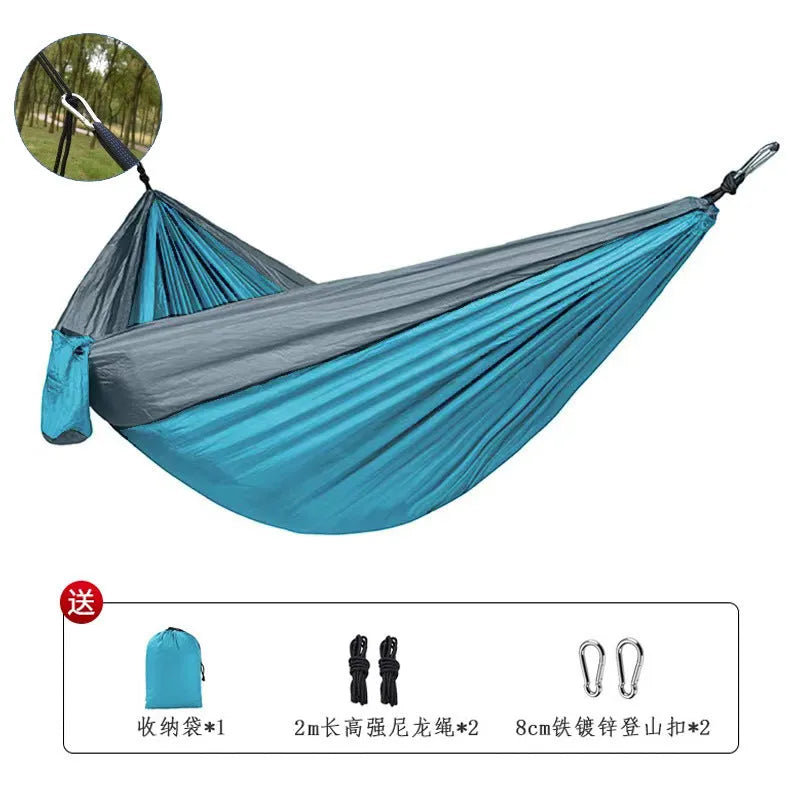 Blue nylon parachute cloth camping hammock hanging between two trees, showing its full 270cm length.