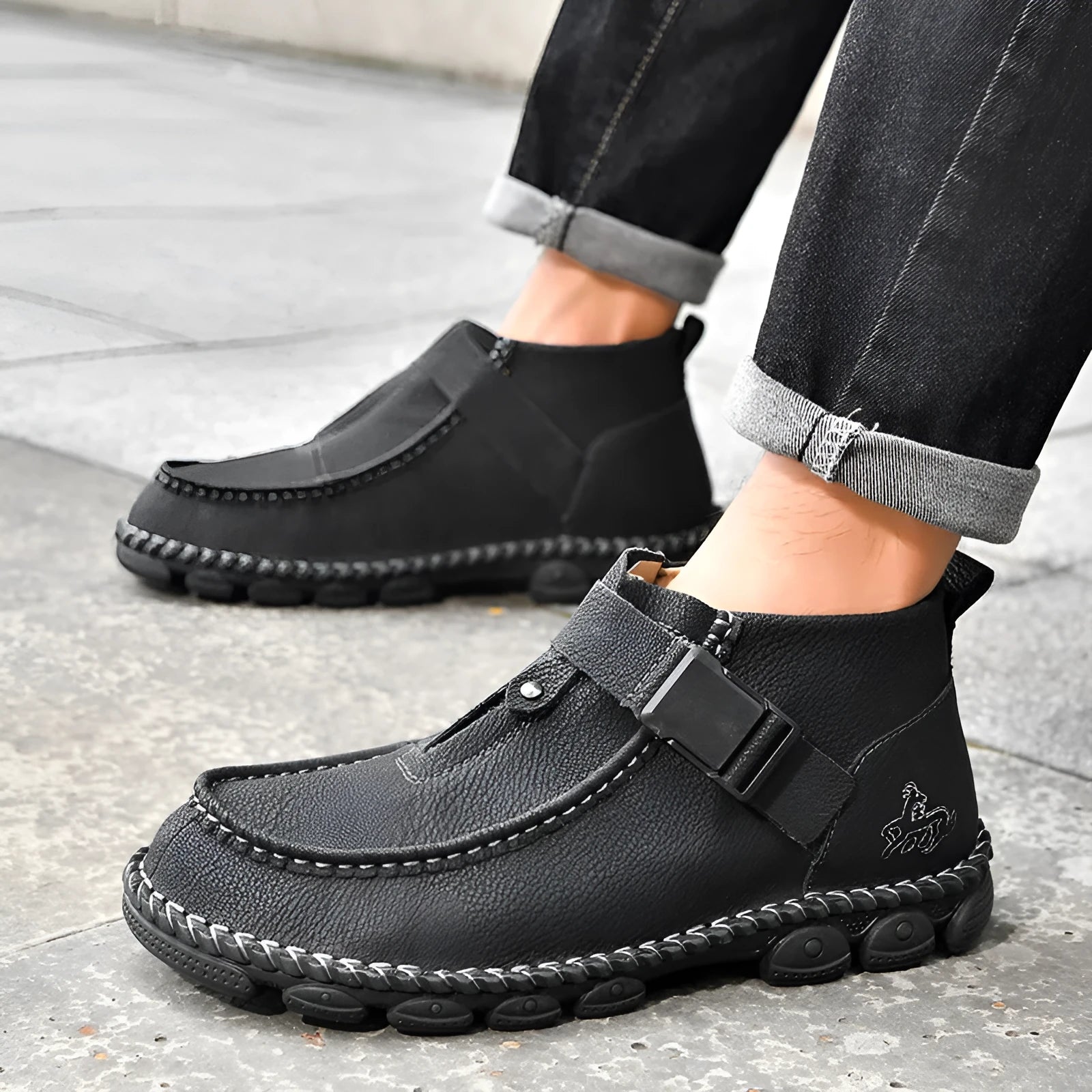 Men's black casual slip-on flat shoes with visible handmade stitching around the sole.