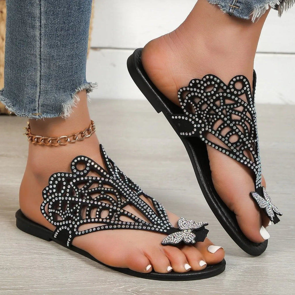 Women's black slip-on sandals with rhinestone decoration and flip-toe design on a white background.