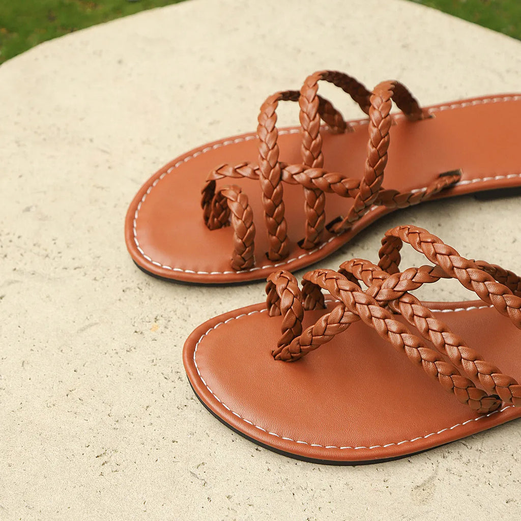 Women's woven clip-toe sandals in black, showing flat rubber sole and Roman gladiator style.