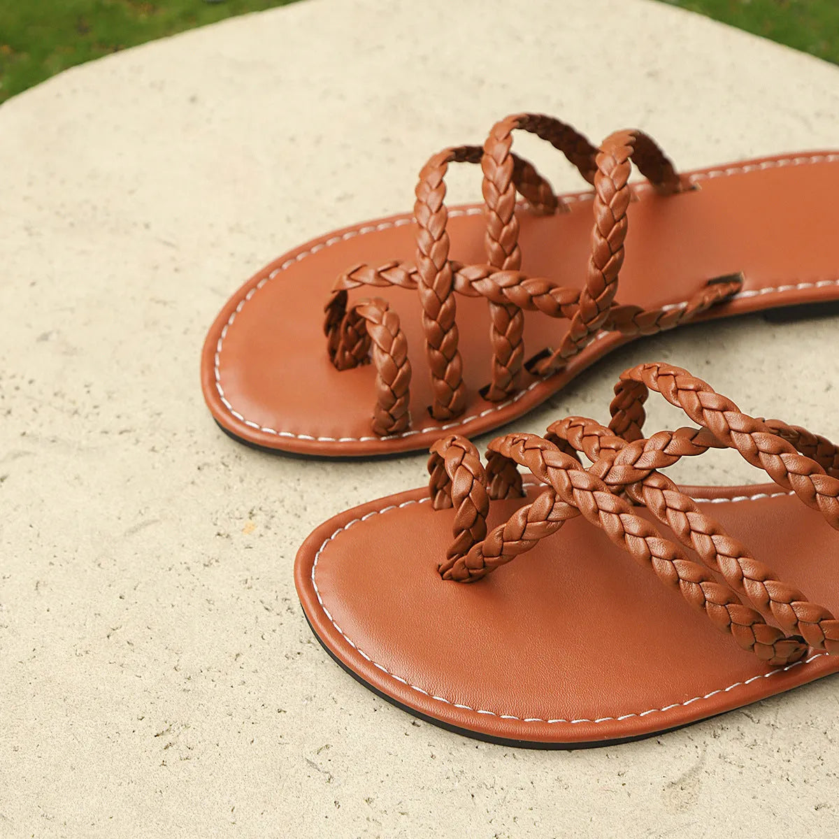 Women's woven clip-toe sandals in black, showing flat rubber sole and Roman gladiator style.
