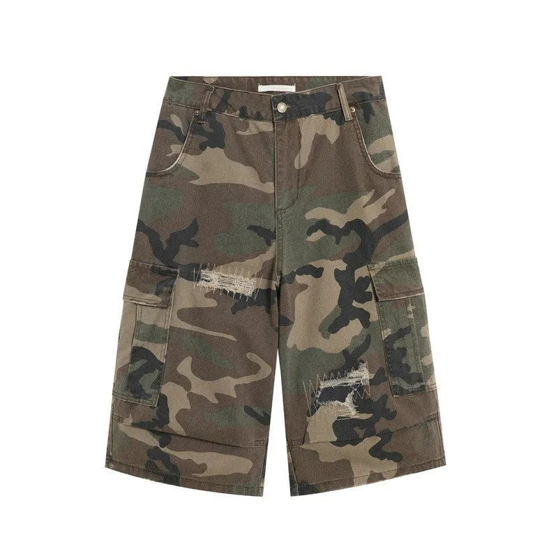 Man wearing loose fit camouflage print cropped jeans with ripped knees and patchwork details.