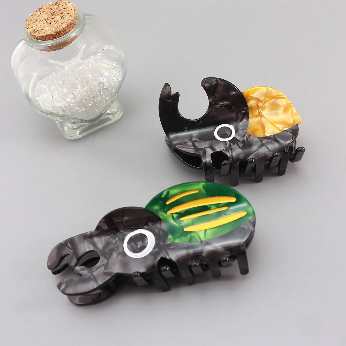 Handmade cartoon beetle grip brooch made from cellulose acetate in green, orange, or white insect designs.