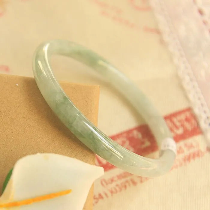 Green handmade geometric jade waxy bracelet with adjustable sizing on a wrist.