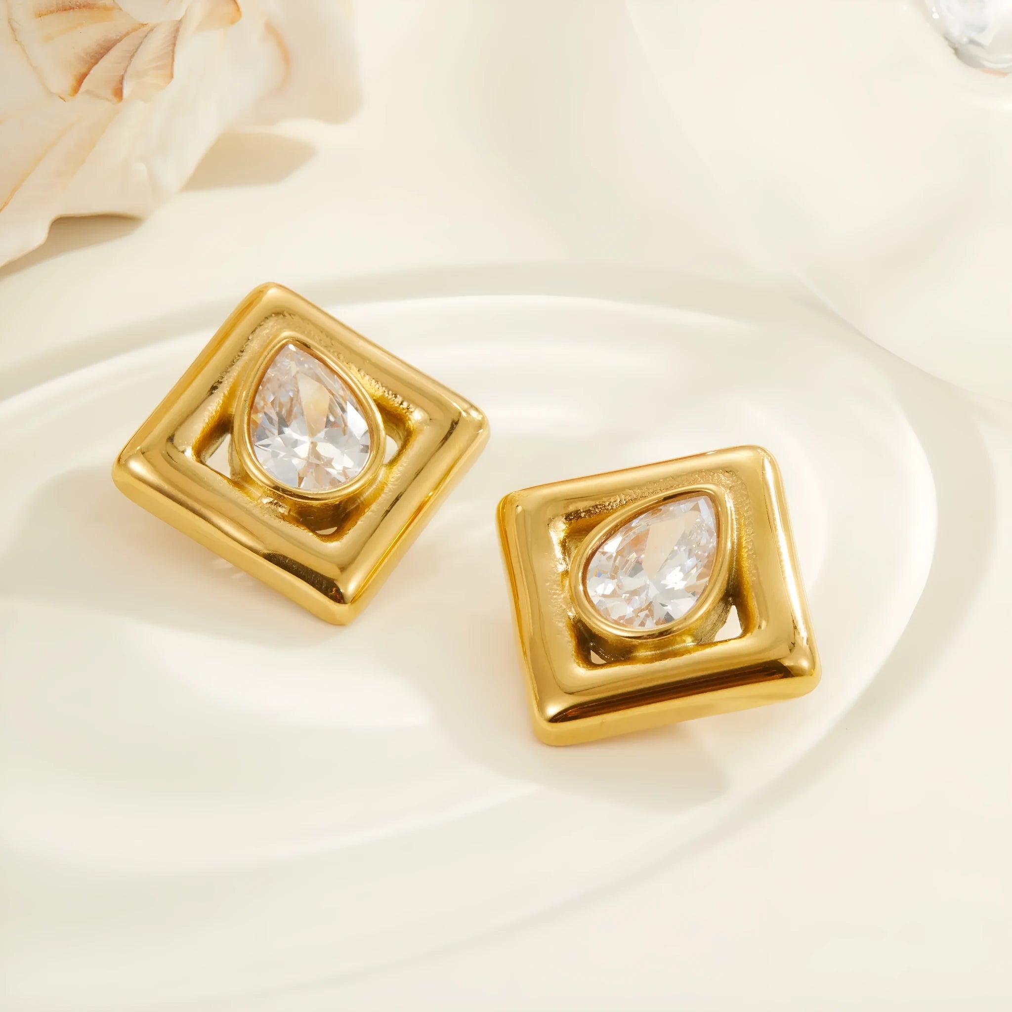 Geometric gold stud earrings with a water drop zircon stone inlaid in the centre.