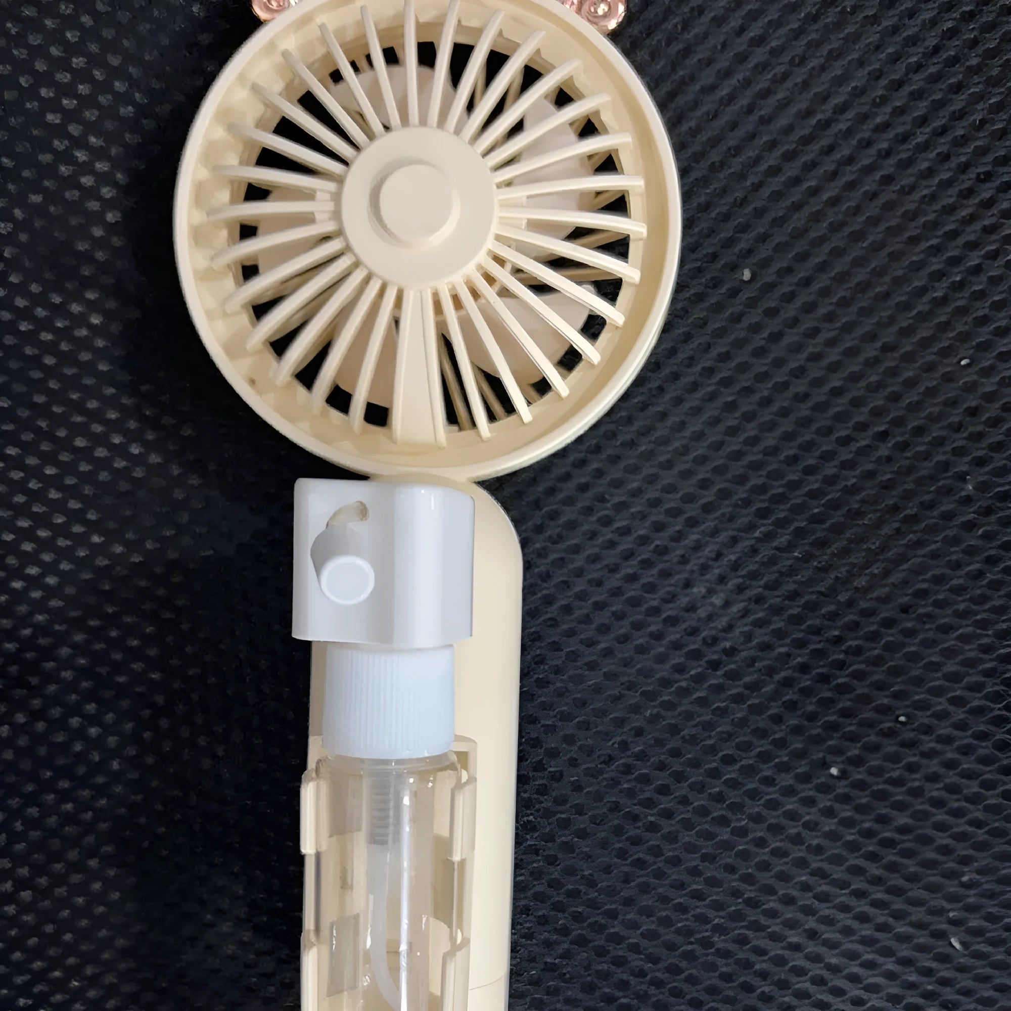 Plastic USB rechargeable personal nozzle fan in apricot colour on a desk