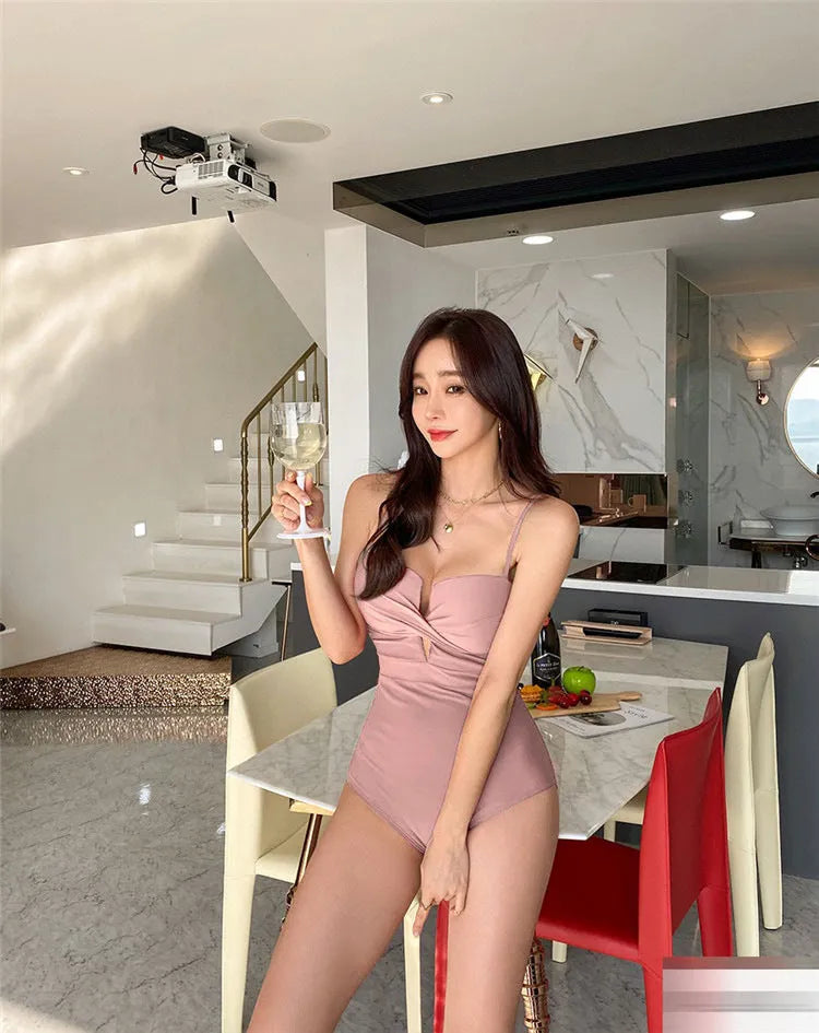 Women's solid colour spaghetti strap one-piece swimsuit with push-up design in white, pink, or brown.